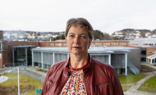 Kvinne rektor med alvorlig ansiktsuttrykk - i bakgrunn universitetscampus. Foto